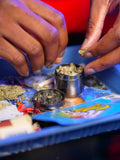 Herb grinder in use on blue tray, urban smoke-shop lifestyle