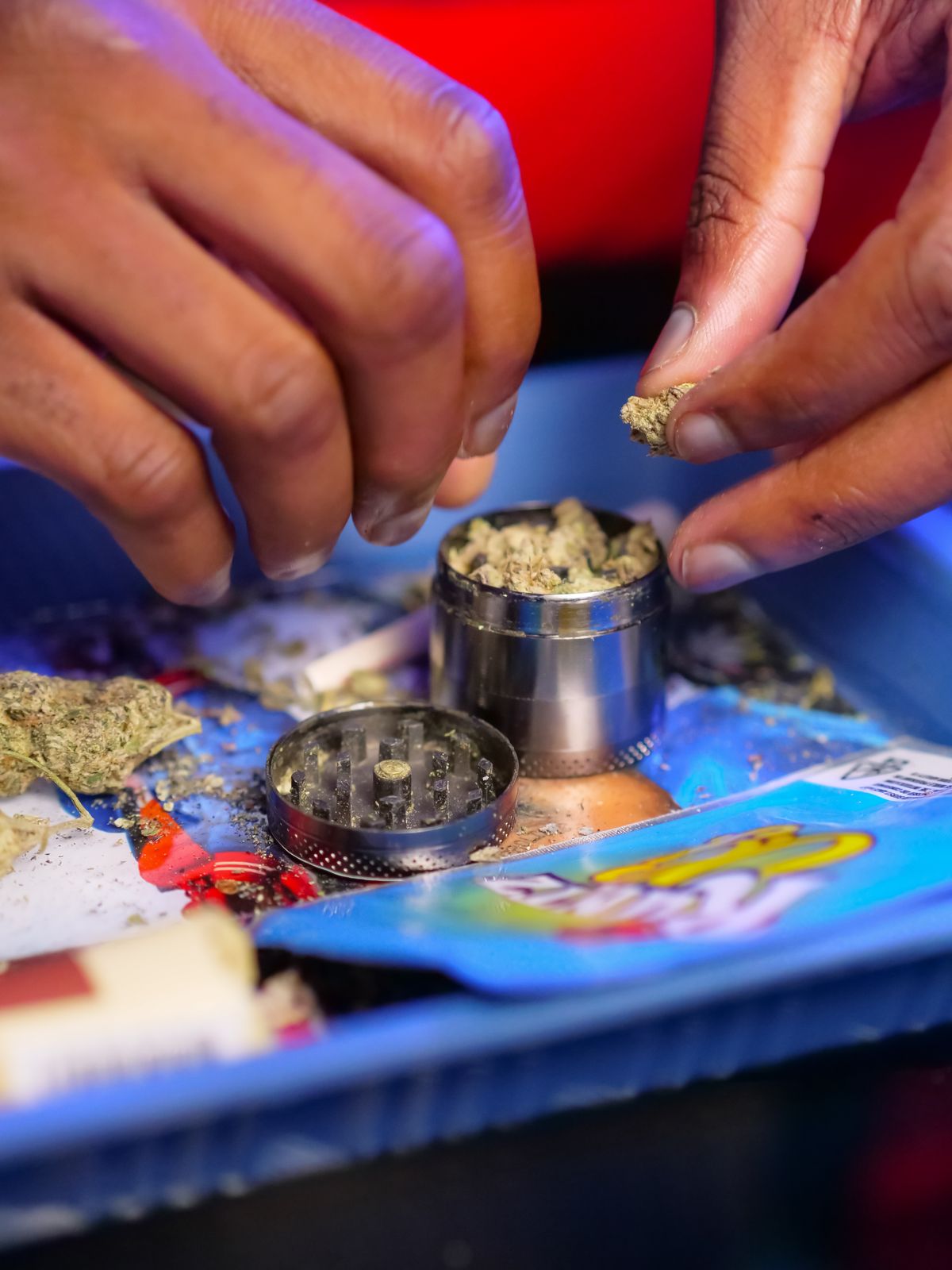 Herb grinder in use on blue tray, urban smoke-shop lifestyle