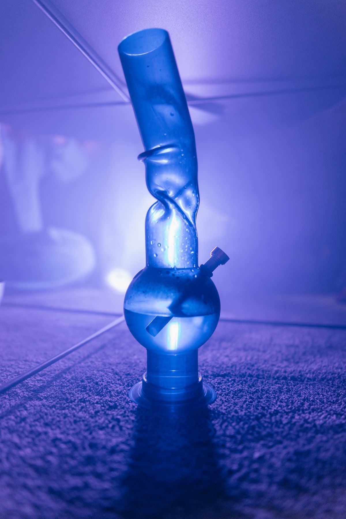 Glass water pipe on stand in moody blue urban lighting